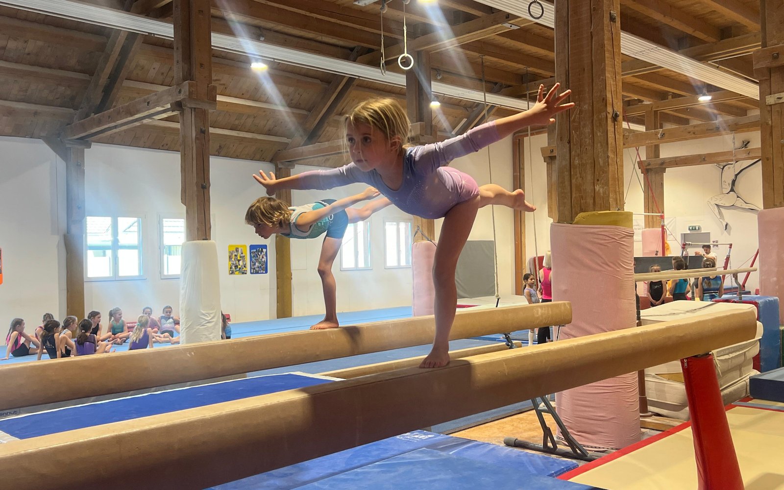 Kind in Standwaage auf dem Schwebebalken beim Basisturnen